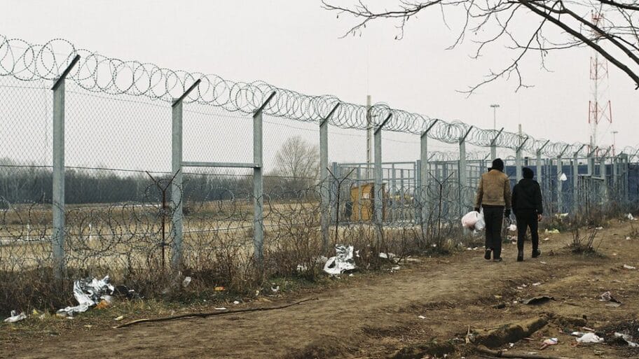 106013934 8twoyoungmenwalkingbythefence